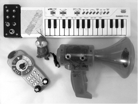 Figure 7-1: A selection of circuit-bent instruments and toys. Note the black box on the keyboard and the new bits on the other three: the knobs, switches, and bare metal contacts allow us to tinker with the toys’ pitch and tone on the fly, while the jacks allow us to amplify the output (and, in the case of the megaphone, pump our own signal into the input). 